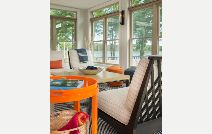 Pops of colors in beachside sunroom offer a bright contrast to neutral upholstery by Blue Jay Design of Wellesley, MA