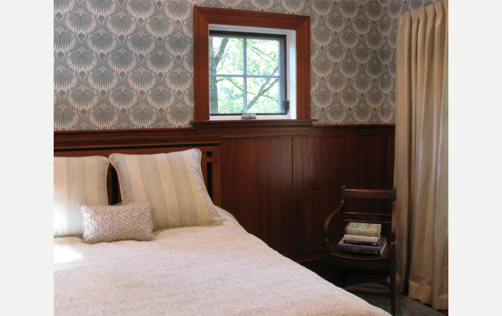 Bold patterned wallpaper, traditional mahogany millwork and neutral textiles in a guest bedroom by Blue Jay Design of Wellesley, MA